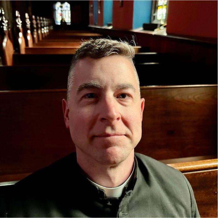 Father Christopher Pyles posing in a pew at Grace & St. Peter's Church